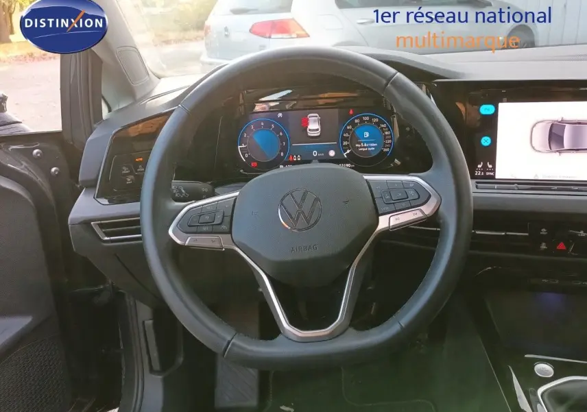 Vue intérieure centrée sur le volant et le tableau de bord numérique de la Volkswagen Golf 1.5 TSI gris Urano, année 2024.