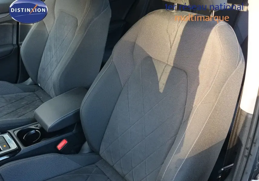 Gros plan sur les sièges avant gris noir de la Volkswagen Golf 1.5 TSI 130CH Style 2024, avec accoudoir central et coutures apparentes.