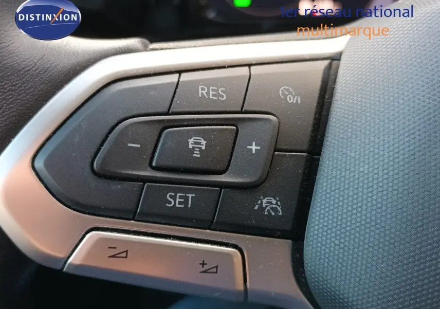 Gros plan sur les commandes au volant côté gauche de la Volkswagen Golf gris Urano 2024, boutons de régulateur de vitesse et assistance.