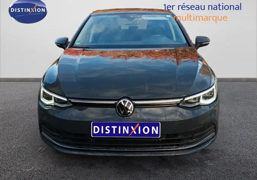 Vue frontale d'une Volkswagen Golf 1.5 TSI 130CH Style gris Urano avec phares LED allumés sur fond neutre.