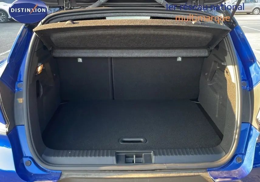 Coffre ouvert d'un Renault Captur E-Tech hybride 2025 bleu iron metal avec toit noir, vue arrière en extérieur.
