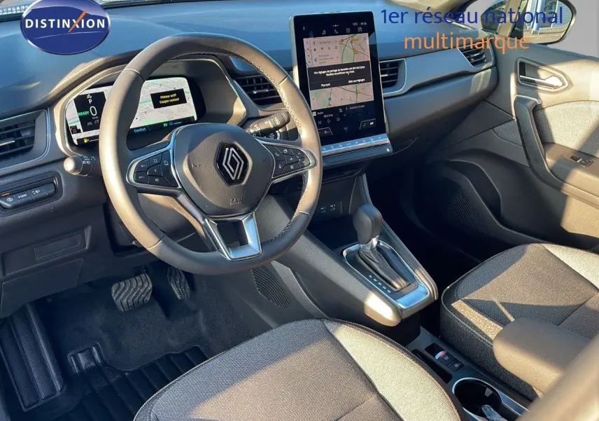 Intérieur Renault Captur E-Tech 2025 vu côté conducteur, volant multifonction et écran tactile central lumineux.