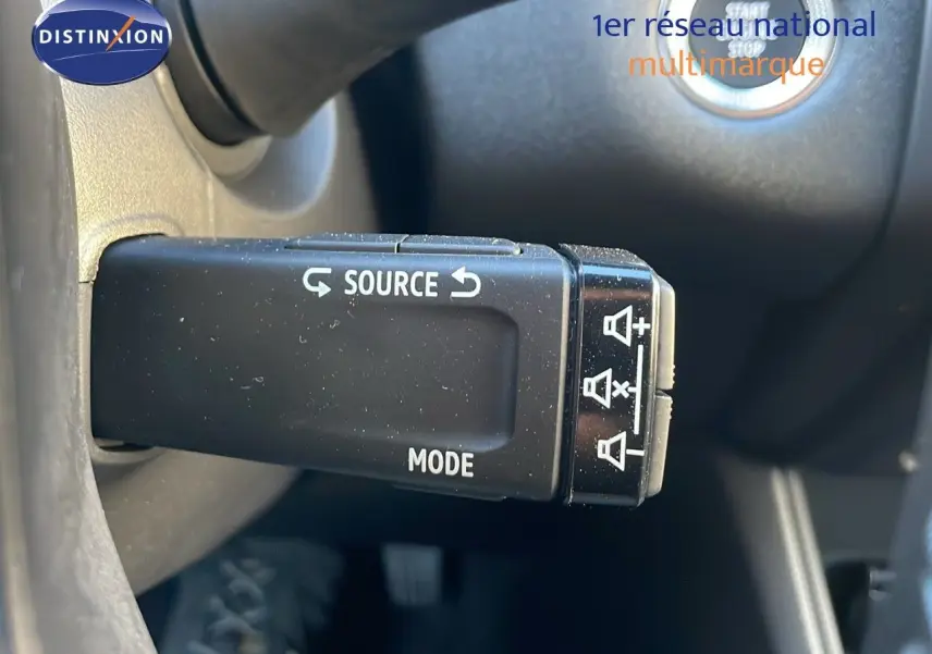 Gros plan sur la commande au volant du Renault Captur E-Tech hybride 2025, avec bouton source et mode visible.