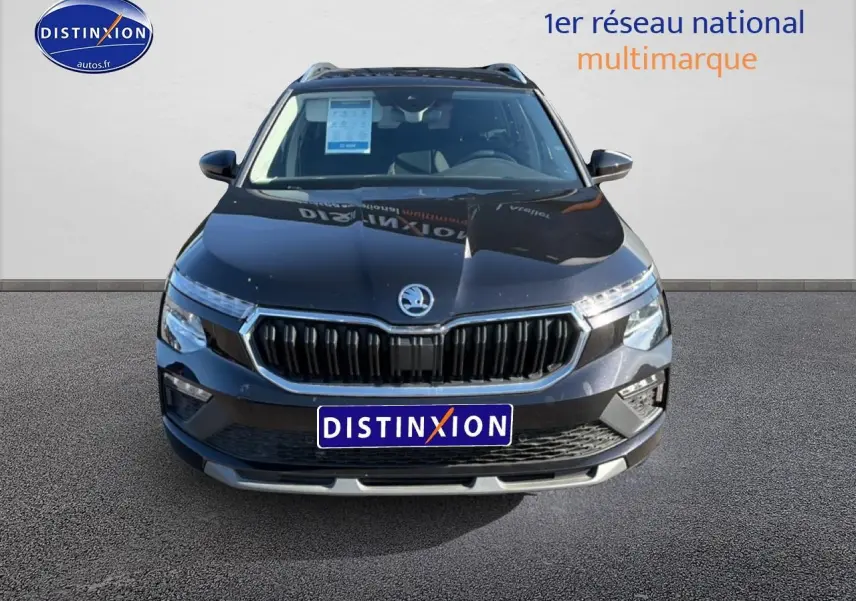 Vue avant d'un Skoda Kamiq noir 2025 avec calandre chromée et feux LED, sur fond neutre avec logo Distinxion.