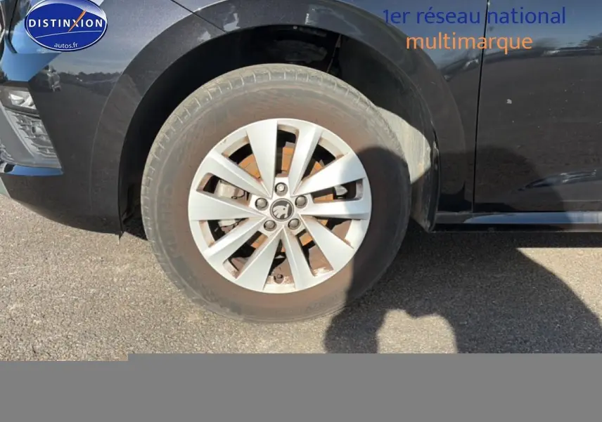 Gros plan sur la roue avant gauche et partie latérale noire d'une Skoda Kamiq 2025 avec jante alu et calandre chromée.