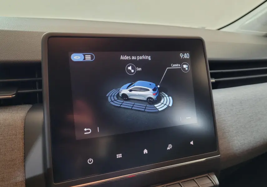 Écran tactile intérieur montrant l'aide au parking avec vue 3D d'une Renault Clio bleue, tableau de bord moderne.