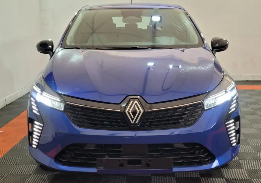 Vue frontale d'une Renault Clio Evolution Blue dCi 100 2025 en bleu avec phares LED allumés et calandre noire.