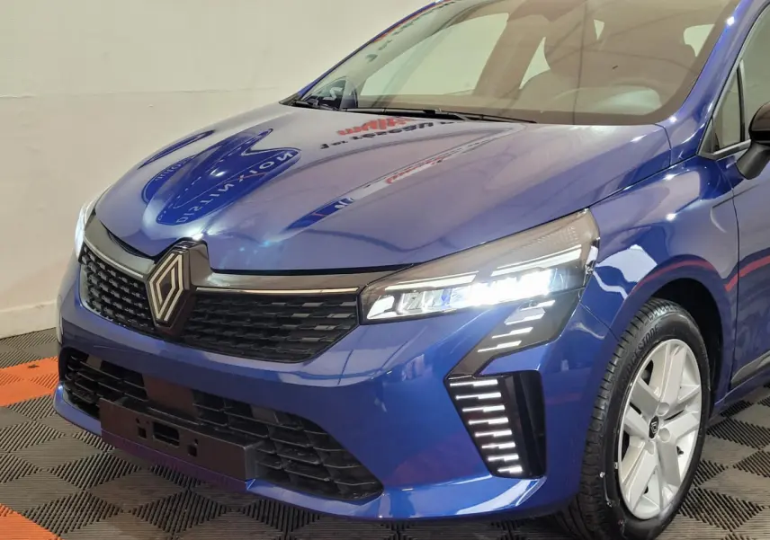 Vue 3/4 avant droite d'une Renault Clio Evolution Blue dCi 100 bleu avec phares LED allumés et jantes argentées.