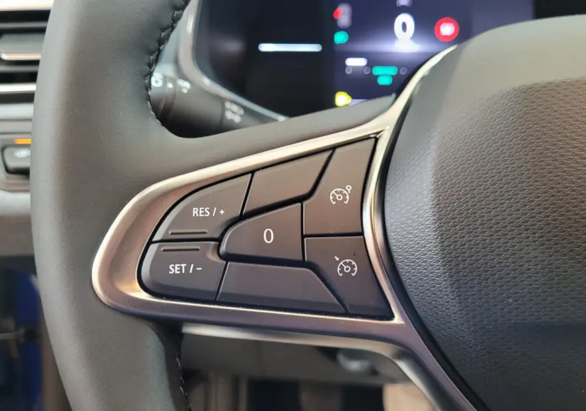 Gros plan sur les commandes du régulateur de vitesse à gauche du volant de la Renault Clio bleu 2025.