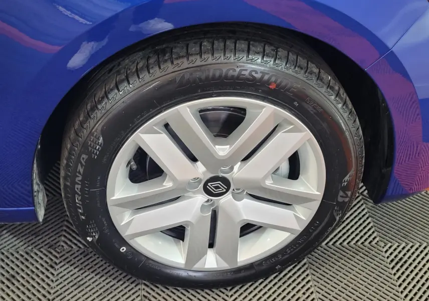 Gros plan sur la roue avant droite d’une Renault Clio bleu 2025 avec jante argentée et logo Renault central.