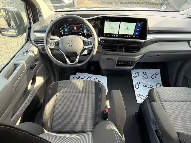 Vue intérieure avant du Volkswagen Transporter T7 ProCab Business 2026 en graphite dust, avec tableau de bord numérique et écran tactile large.