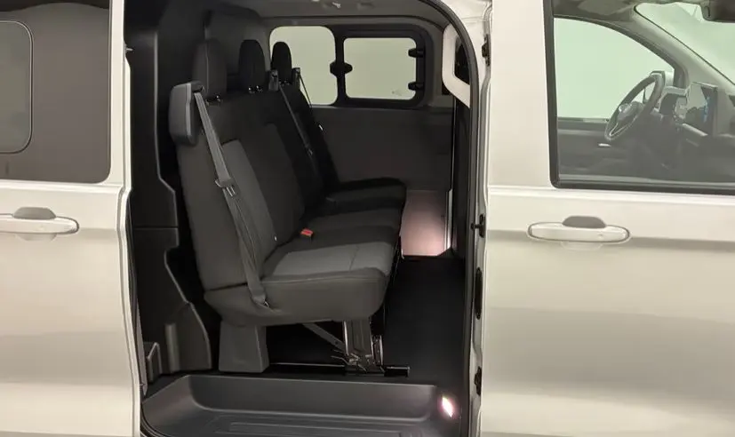 Vue latérale intérieure du Volkswagen Transporter ProCab gris clair, montrant les sièges passagers et l'ouverture de la porte coulissante.