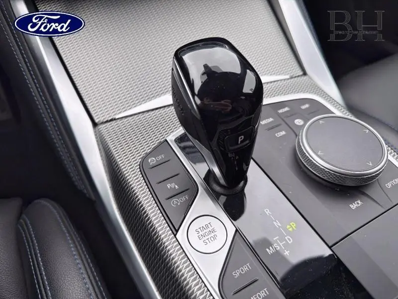 Le levier de vitesses noir brillant et les commandes argentées d'une console centrale intérieure, vue rapprochée.