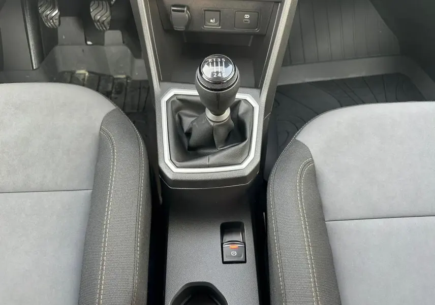 Vue rapprochée de la console centrale intérieure avec levier de vitesse manuel et frein de parking électrique sur Dacia Sandero Stepway.