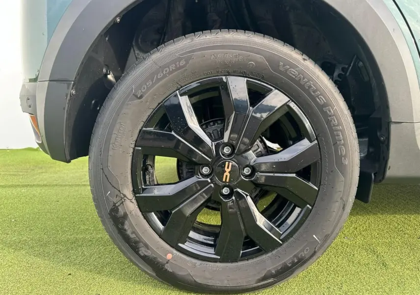 Gros plan sur la jante noire brillante 16 pouces du côté avant droit d'une Dacia Sandero Stepway vert cèdre.