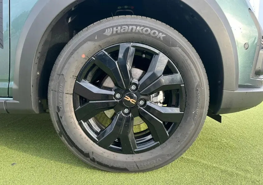 Gros plan sur la roue avant gauche noire brillante d'une Dacia Sandero III Stepway vert cèdre avec jante aluminium 16 pouces.