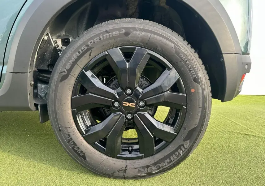 Gros plan sur la roue avant droite de la Dacia Sandero III Stepway vert cèdre avec jante aluminium noire brillante.
