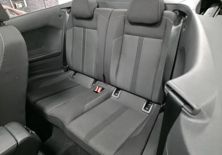 Vue rapprochée de la banquette arrière tissu noire du Volkswagen T-Roc Cabriolet 2024, avec appuis-tête et ceintures visibles.