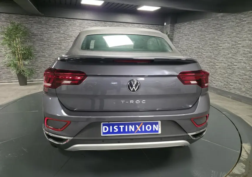 Vue arrière d'un Volkswagen T-Roc Cabriolet gris métallisé 2024 avec capote textile noire et feux arrière LED.