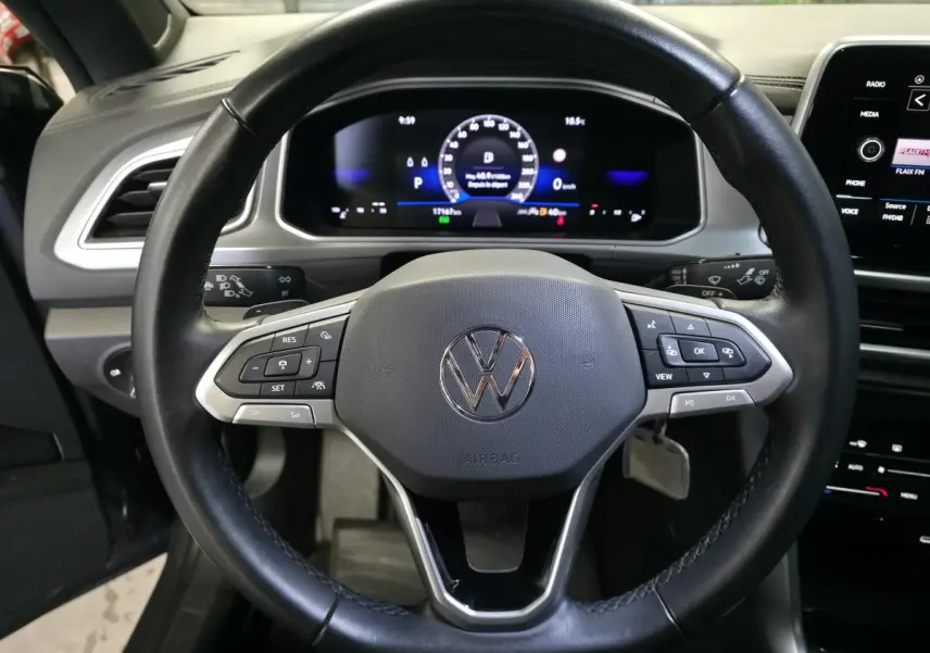 Vue rapprochée du volant en cuir noir et du tableau de bord numérique du Volkswagen T-Roc 2024 cabriolet gris.