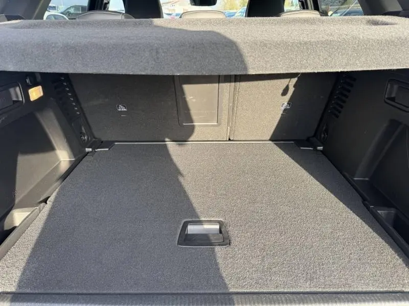 Coffre spacieux du Peugeot 3008 2024 noir, vue intérieure arrière avec cache-bagages et revêtement gris.