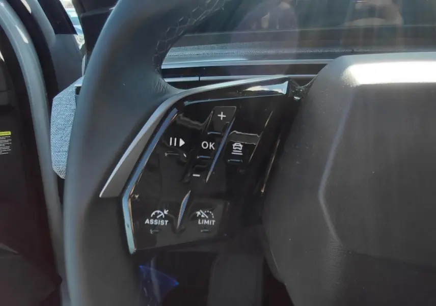 Gros plan sur les commandes à gauche du volant du Peugeot 5008 blanc 2025, avec logo lion distinctif.