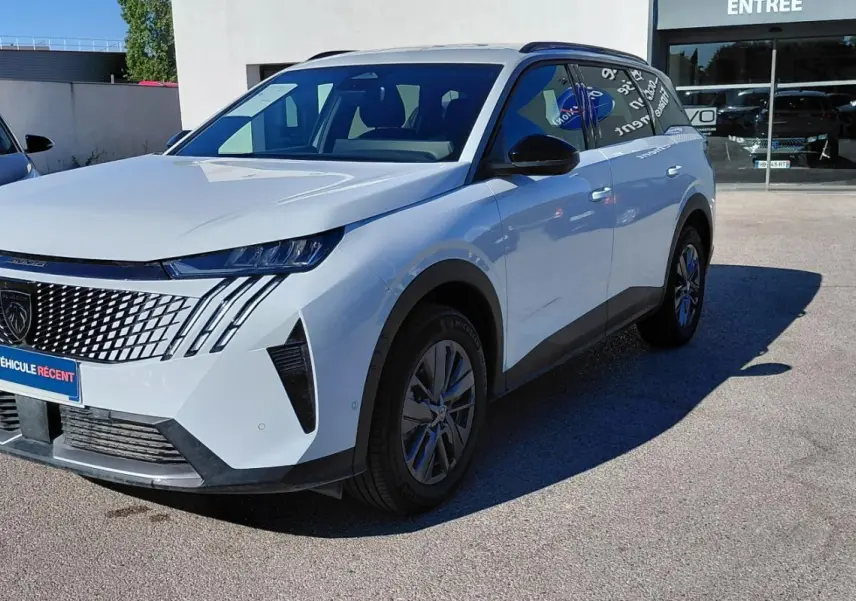 Peugeot 5008 Hybrid blanc vue 3/4 avant droit, avec calandre distinctive et feux LED verticaux.