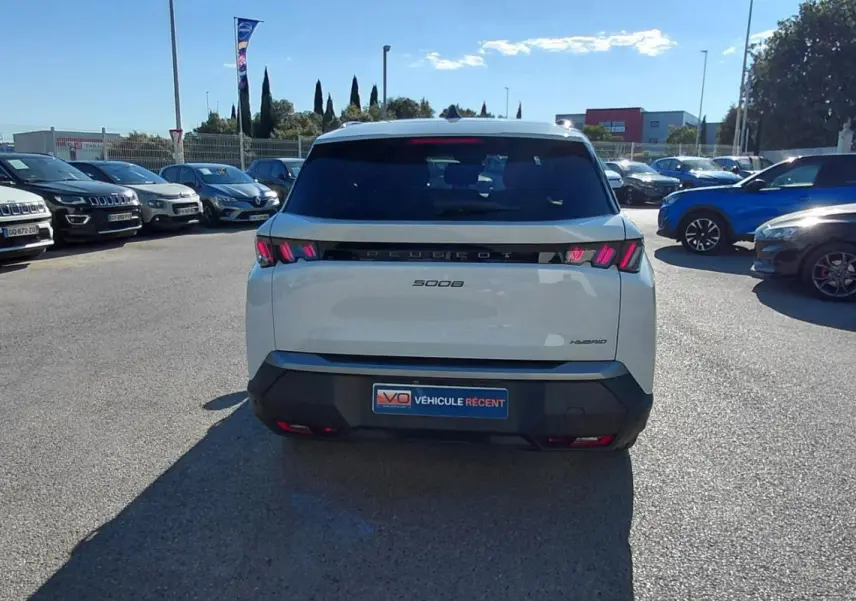 Vue arrière d'un Peugeot 5008 blanc 2025 Hybrid 145 ch avec feux arrière LED distinctifs, stationné en extérieur.