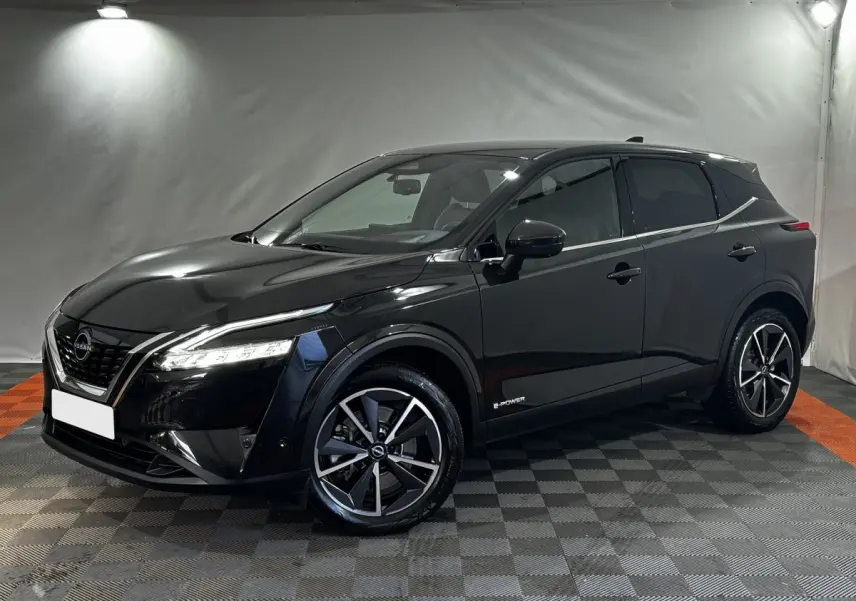 Nissan Qashqai e-Power noir en 3/4 avant droit, avec jantes alliage et phares LED allumés dans un studio.