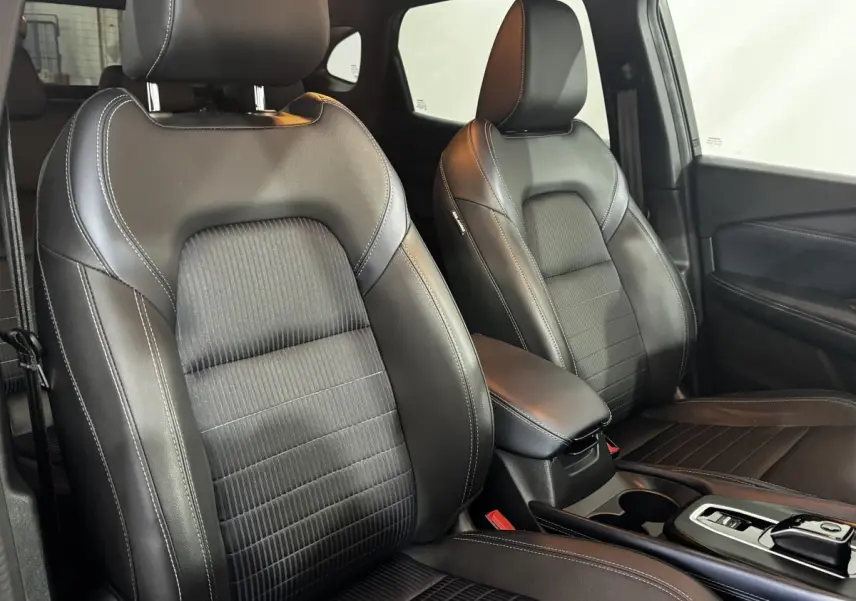 Intérieur du Nissan Qashqai e-Power 2023, vue rapprochée des sièges avant en cuir noir avec surpiqûres blanches.