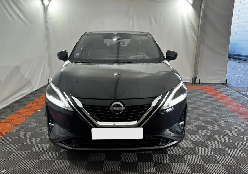 Vue avant d'un Nissan Qashqai e-Power 190 Tekna BVA noir avec phares LED et calandre chromée dans un garage.