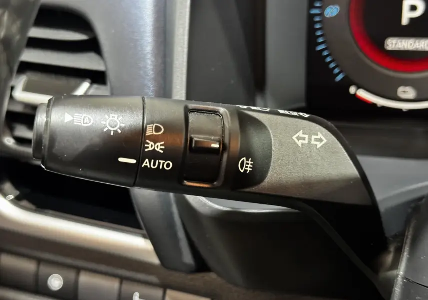 Gros plan sur la commande des phares et clignotants côté gauche du tableau de bord du Nissan Qashqai e-Power noir 2023.