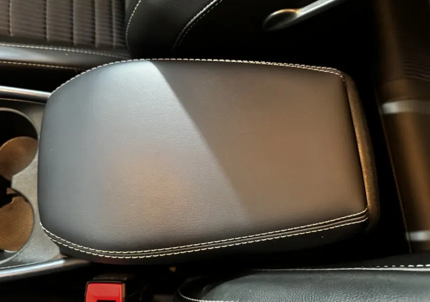Gros plan sur l'accoudoir central en cuir noir avec surpiqûres blanches du Nissan Qashqai e-Power 190 Tekna BVA 2023.