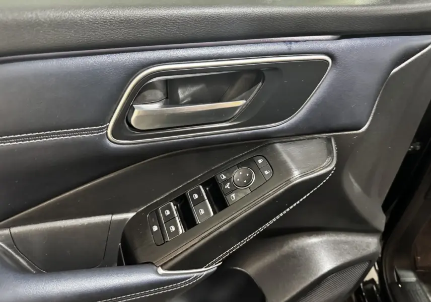 Détail de la porte intérieure côté conducteur du Nissan Qashqai e-Power 190 Tekna 2023 en cuir noir avec commandes électriques.