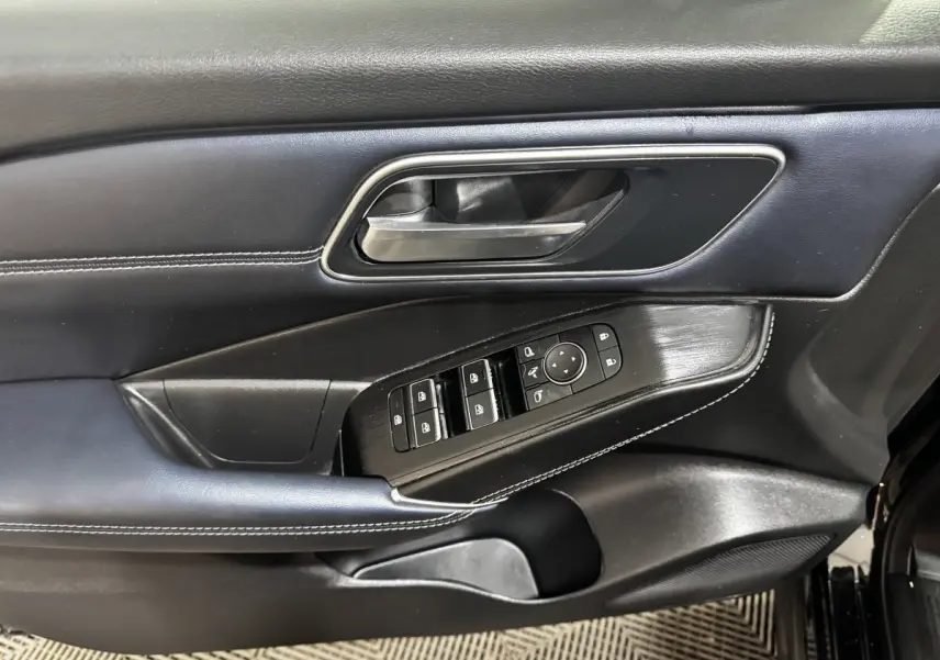 Détail de la porte avant gauche noire du Nissan Qashqai e-Power 190 Tekna avec commandes des vitres et rétroviseurs.