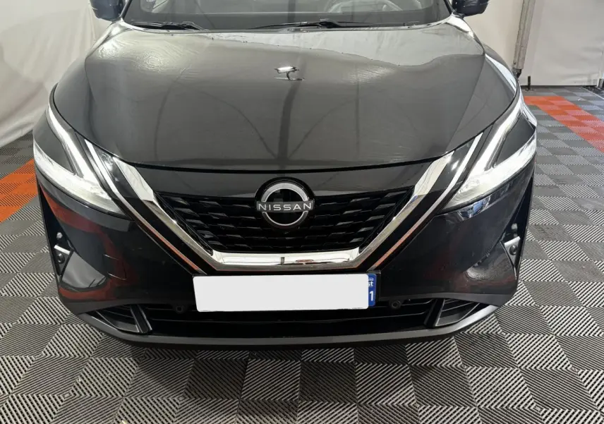 Vue frontale d'un Nissan Qashqai e-Power 190 Tekna BVA noir avec calandre chromée et phares LED allumés.