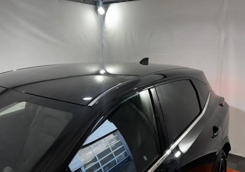 Vue 3/4 arrière droite du Nissan Qashqai e-Power 190 Tekna noir avec vitres teintées dans un garage blanc.