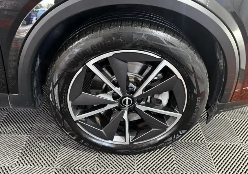 Gros plan sur la roue avant droite noire du Nissan Qashqai e-Power 190 Tekna BVA avec jante alliage bicolore.