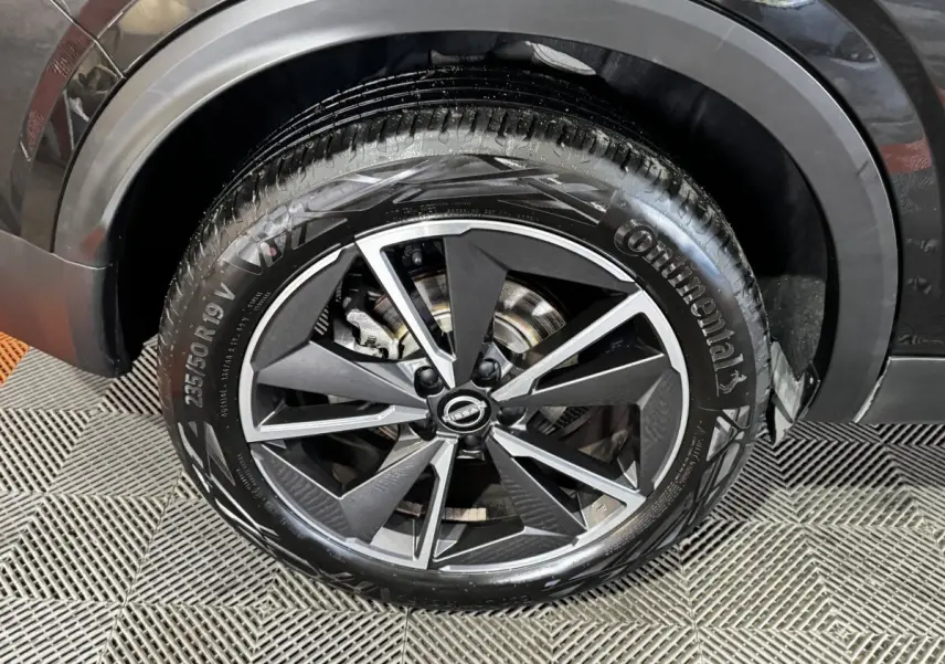 Gros plan sur la roue avant droite noire du Nissan Qashqai e-Power 190 Tekna BVA avec jante alliage bicolore.