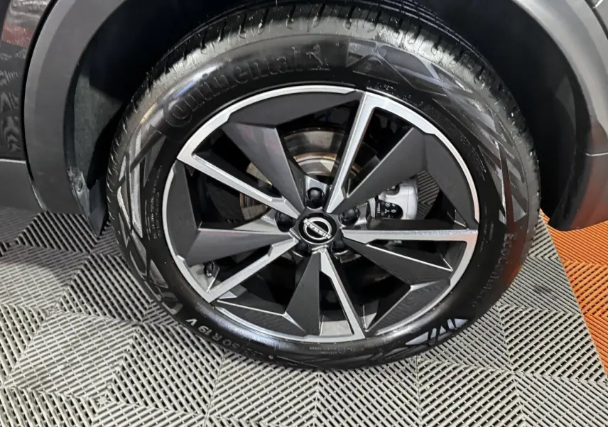Gros plan sur la roue avant droite du Nissan Qashqai e-Power 190 Tekna BVA noir, jante alliage bicolore moderne.