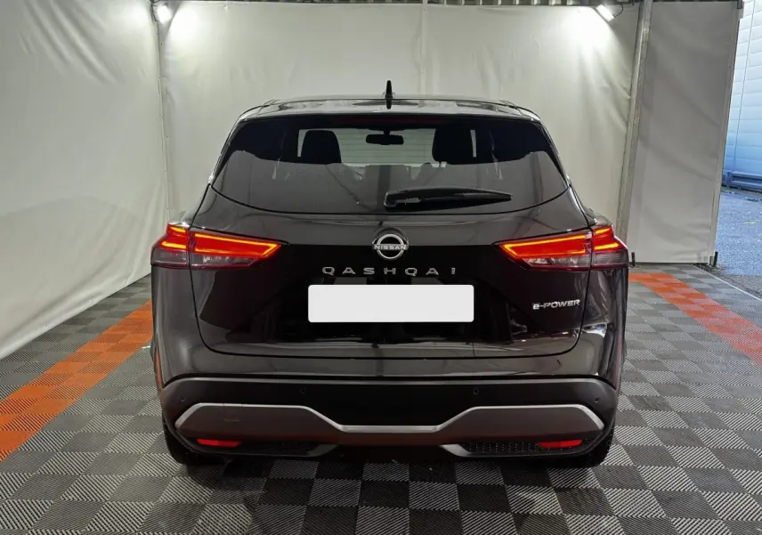 Vue arrière d'un Nissan Qashqai e-Power noir avec feux LED allumés dans un espace intérieur éclairé.