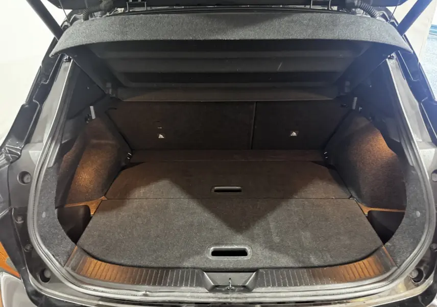 Coffre ouvert noir du Nissan Qashqai e-Power 190 Tekna 2023, vue intérieure montrant l'espace de chargement plat et éclairé.
