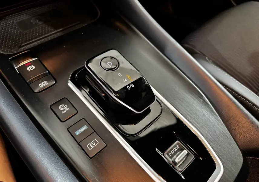 Gros plan sur la console centrale noire du Nissan Qashqai e-Power 190 Tekna 2023 avec sélecteur de boîte auto et boutons de mode.