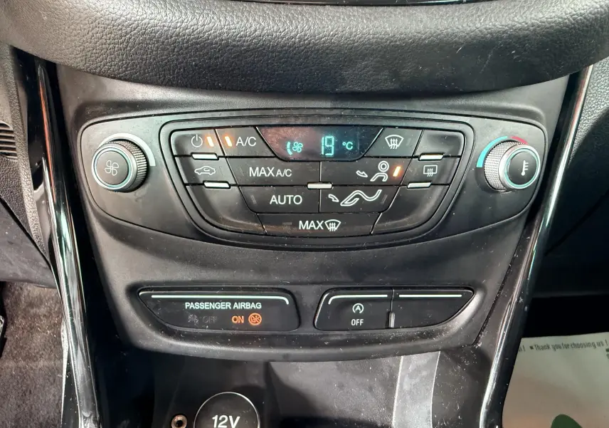 Vue rapprochée de la console centrale noire avec commandes de climatisation et affichage digital à 19°C.