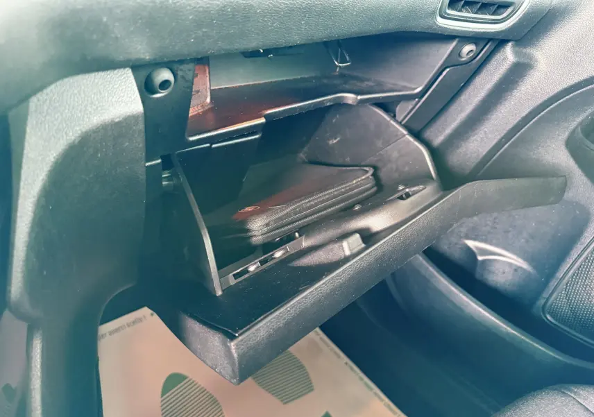 Gros plan sur la boîte à gants ouverte côté passager du Ford B-MAX 2014, intérieur noir avec pochette visible.