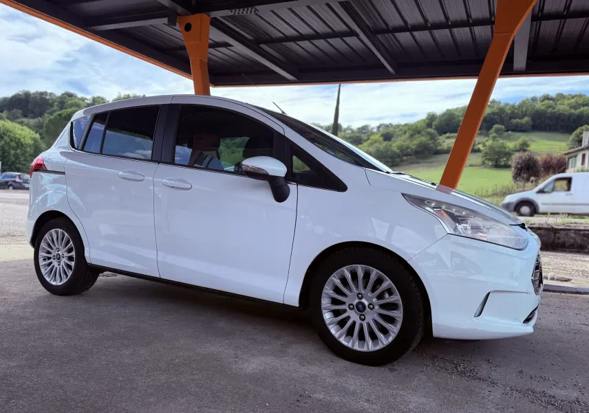 Ford B-MAX blanc en vue de profil côté gauche sous abri avec jantes alliage et vitres teintées.