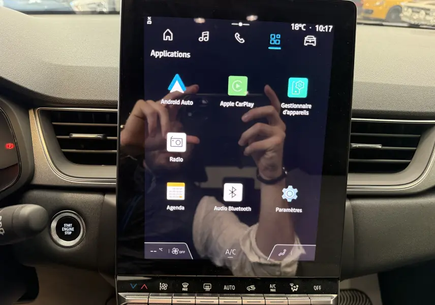 Écran tactile central du tableau de bord du Renault Captur 2025, avec commandes climatisation et bouton start/stop visibles.
