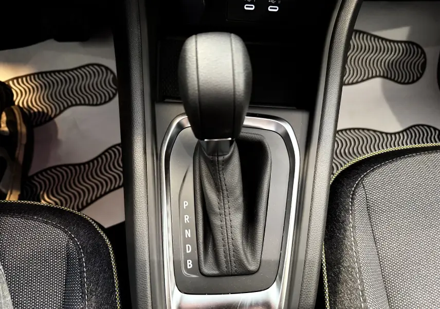 Le levier de vitesses automatique noir du Renault Captur 2025, entouré de coutures jaunes sur les sièges sombres.