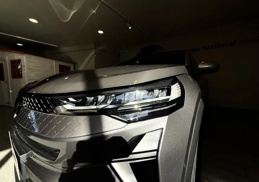 Gros plan sur l'avant droit du Renault Captur gris Cassiopée métal, mettant en valeur le phare LED et la calandre distinctive.