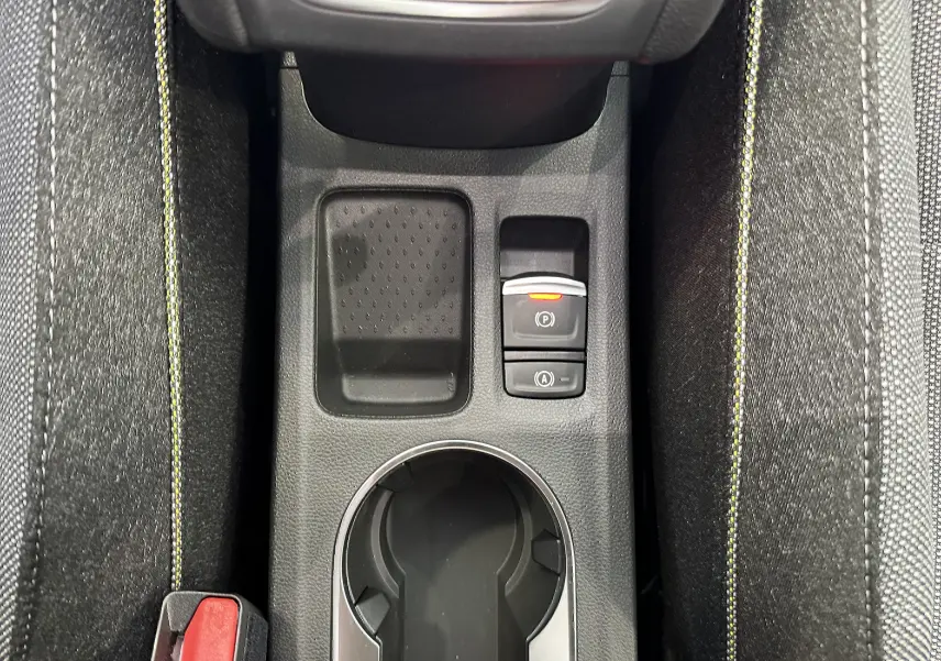 Vue plongeante sur la console centrale du Renault Captur gris cassiopée, avec porte-gobelet et boutons de frein à main électrique.